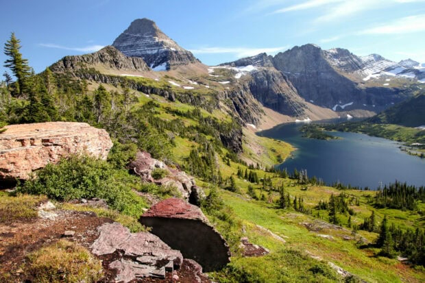 A scenic view of the mountain and lake in Glacier National Park on a clear day, 2K Desktop Wallpaper