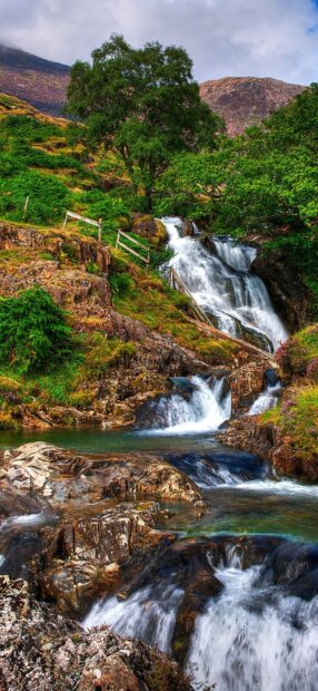 A beautiful waterfall flows through rocks and greenery in Wales Wallpapers landscape, HD Phone Wallpaper