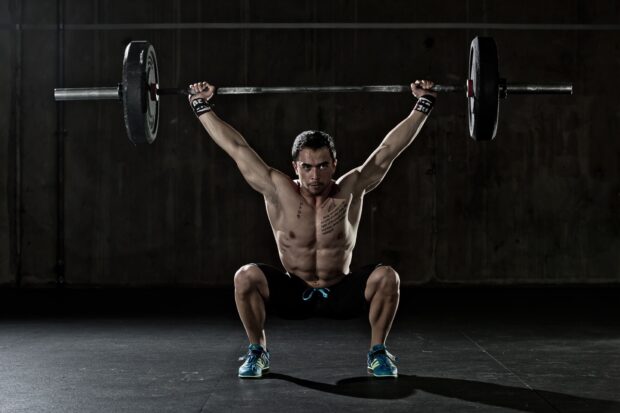 A muscular athlete is performing a snatch lift with a heavy barbell during Crossfit training, HD Desktop Wallpaper