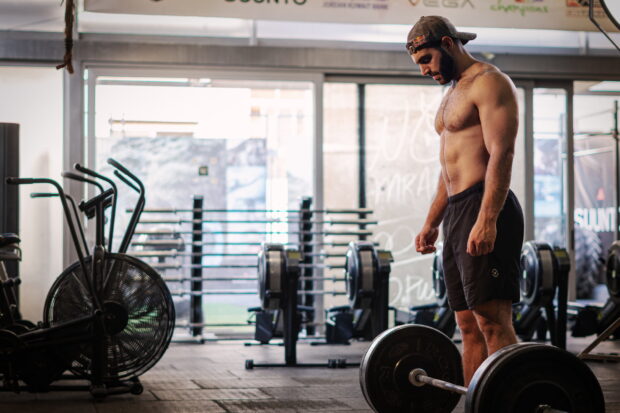A muscular man is standing in a gym preparing to lift a heavy barbell during a Crossfit workout, 2K Desktop Wallpaper