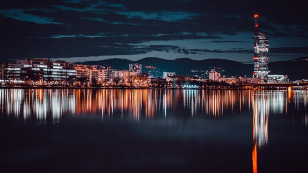 The night cityscape with illuminated buildings reflects on the calm water in Austria Wallpapers, 4K Desktop Wallpaper