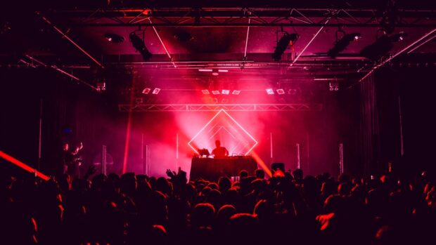A DJ is performing live on stage with vibrant red lighting at the nightclub concert, HD Desktop Wallpaper