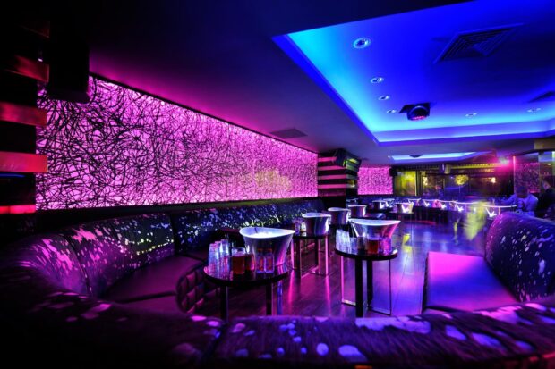 The nightclub interior displays vibrant purple lighting and modern seating arrangements, HD Desktop Wallpaper