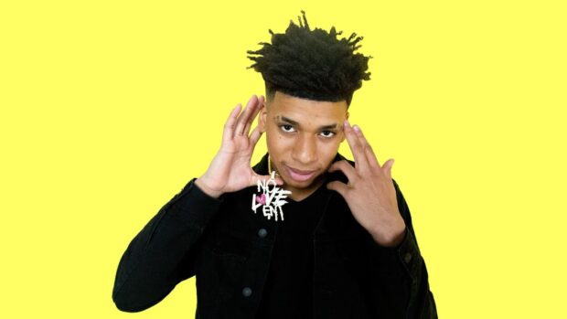 Young man with Nle Choppa hairstyle wearing a black jacket on a yellow background
