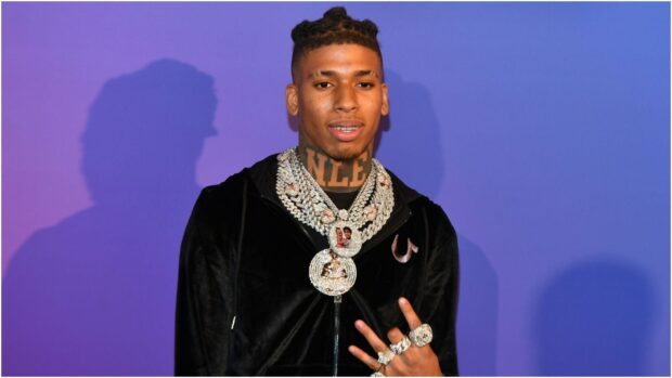 Nle Choppa wearing diamond chains and rings against a purple background