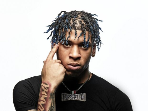 Nle Choppa with blue twists hairstyle wearing a black shirt and a Top Shotta necklace