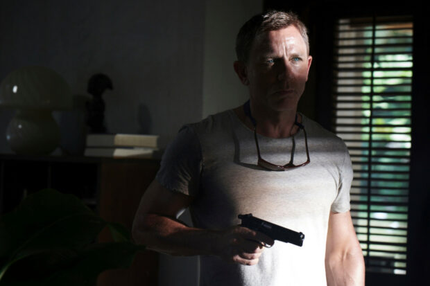 A man holding a gun in a dimly lit room from No Time To Die, HD Desktop Wallpaper