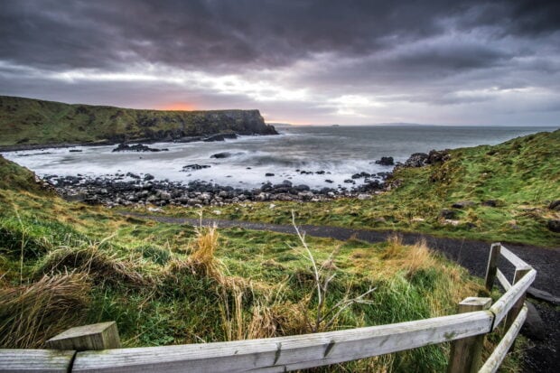 A serene view of Northern Ireland coastline with cliffs and waves under a cloudy sky, HD Desktop Wallpaper
