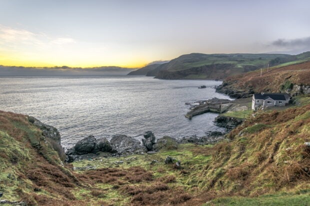 A scenic view of Northern Ireland coastline with hills and a house near the sea, HD Desktop Wallpaper