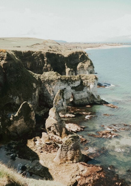 A scenic coastal landscape in Northern Ireland features cliffs and rock formations, 2K Phone Wallpaper