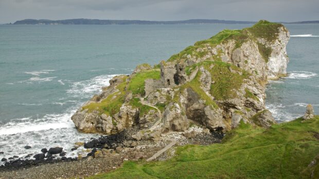 A scenic view of Northern Ireland with ancient stone ruins on rocky cliffs by the sea, 2K Desktop Wallpaper