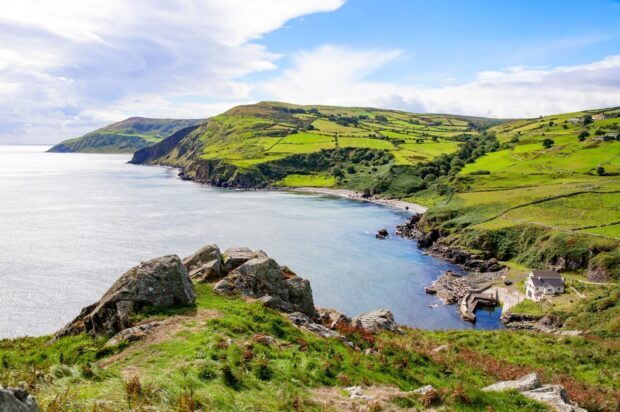 A scenic coastal view with green fields and rocks in Northern Ireland, 2K Desktop Wallpaper