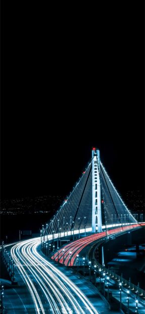 Oakland bridge illuminated with light trails of moving cars at night