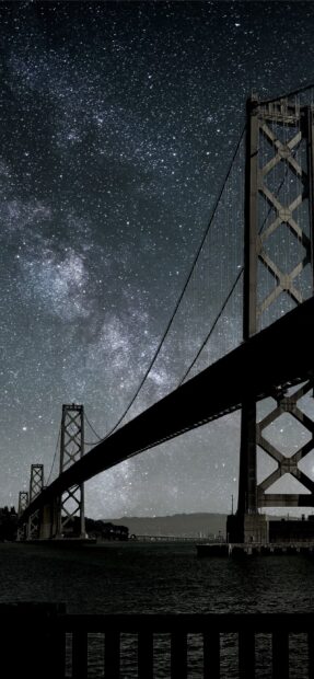 A stunning night view of Oakland bridge under a starry sky background