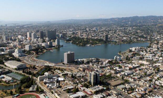 Panoramic view of Oakland city skyline with lake and urban buildings in clear sky
