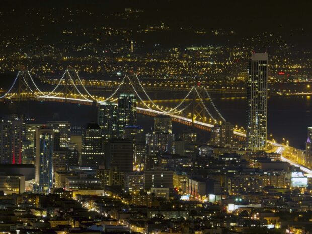 Oakland Wallpaper HD Desktop a nighttime cityscape of Oakland with illuminated buildings and a lit suspension bridge