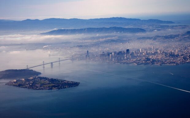 Oakland Wallpaper HD Desktop an aerial view of Oakland city with a bridge and fog over the water and mountains in the background