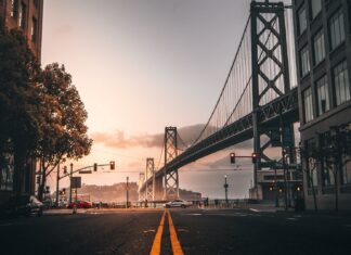 A scenic view of Oakland bridge and street at sunset with cars and buildings
