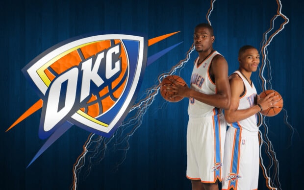 Two Oklahoma City Thunder players stand back to back holding basketballs in front of the team logo with lightning effects