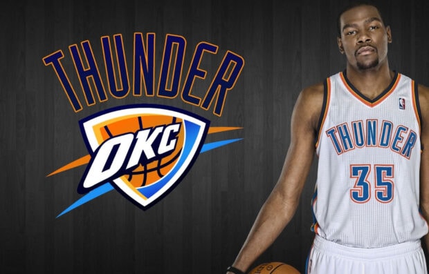 A basketball player wearing an Oklahoma City Thunder jersey standing next to the team logo on a dark background