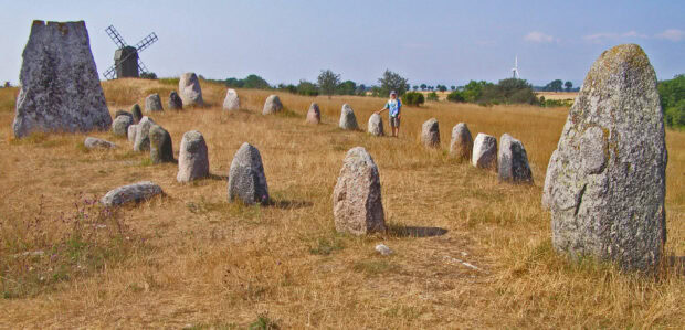 Ancient stone circle on Oland Sweden with a person standing nearby in a dry grassy field