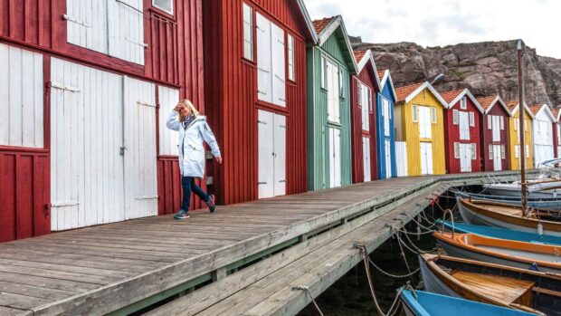 A woman walking by colorful wooden buildings in Oland Sweden
