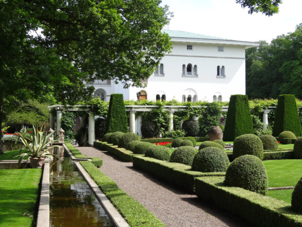 Beautiful garden with trimmed bushes near a white building in Oland Sweden