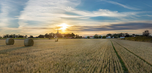 Golden fields and hay bales in Oland Sweden with village and sunset sky