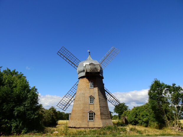 Old windmill in Oland Sweden surrounded by green trees under clear blue sky
