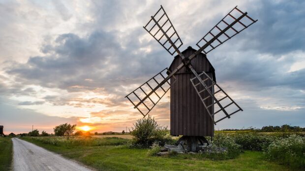 Traditional Oland Sweden windmill near a rural road under a cloudy sunset sky