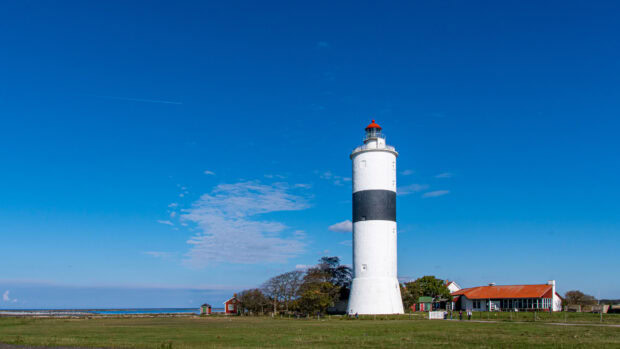 A lighthouse with a black stripe on Oland Sweden under a bright blue sky