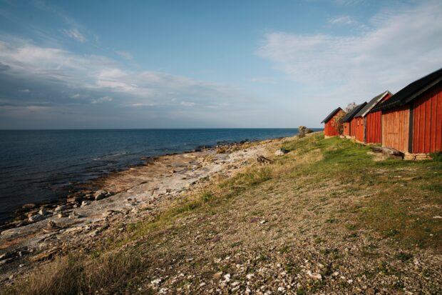 Scenic Oland Sweden coastline with red cabins and rocky shore under blue sky