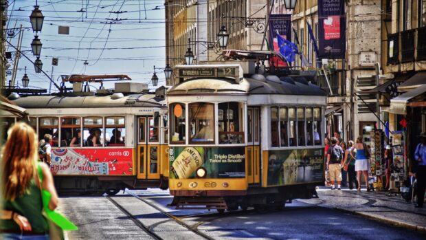 A yellow and red tram cross in Lisbon Portugal with people walking nearby, 4K Desktop Wallpaper