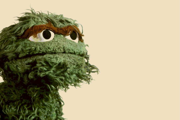 Oscar the Grouch from Sesame Street has a serious expression on a beige background, 2K Desktop Wallpaper