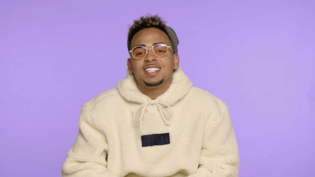 Ozuna is smiling wearing a cream hoodie and glasses in front of a purple background, HD Desktop Wallpaper