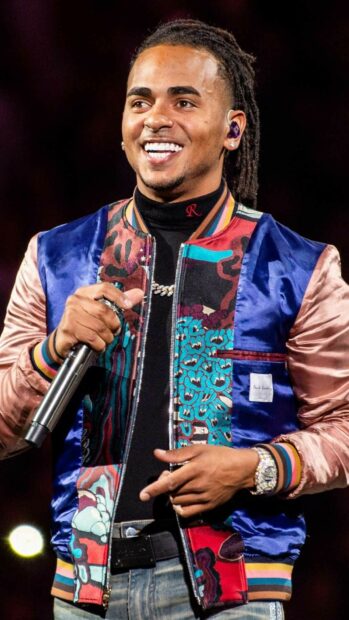 Ozuna Wallpapers showing a joyful moment on stage with colorful jacket, HD Mobile Wallpaper