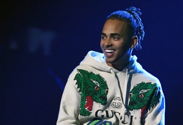 Ozuna Wallpapers features a smiling Ozuna wearing a white hoodie with green designs, HD Desktop Wallpaper