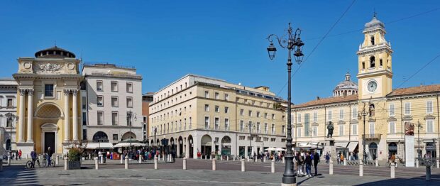 Historic architecture and vibrant city life in Parma Italy with clear blue sky