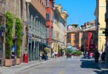 A lively street scene in Parma Italy featuring colorful historic buildings and pedestrians walking on a sunny day