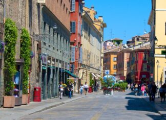 A lively street scene in Parma Italy featuring colorful historic buildings and pedestrians walking on a sunny day