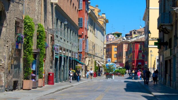 A lively street scene in Parma Italy featuring colorful historic buildings and pedestrians walking on a sunny day