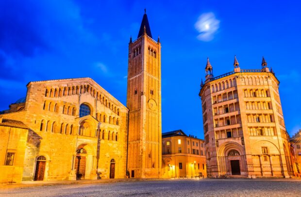 The historic architecture of Parma Italy is illuminated under a bright evening sky