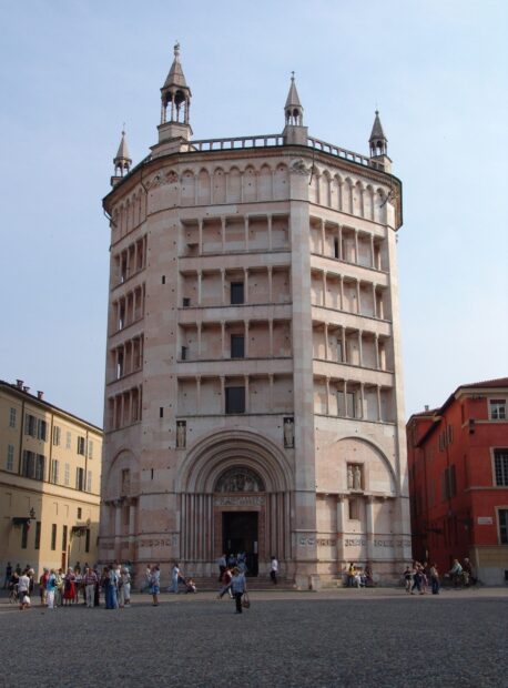 The historic baptistery building in Parma Italy with people gathered outside in the square