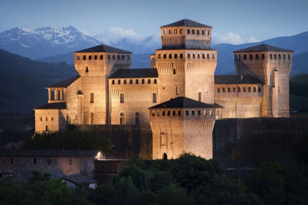Ancient fortress in Parma Italy lit up at dusk with mountains in the background