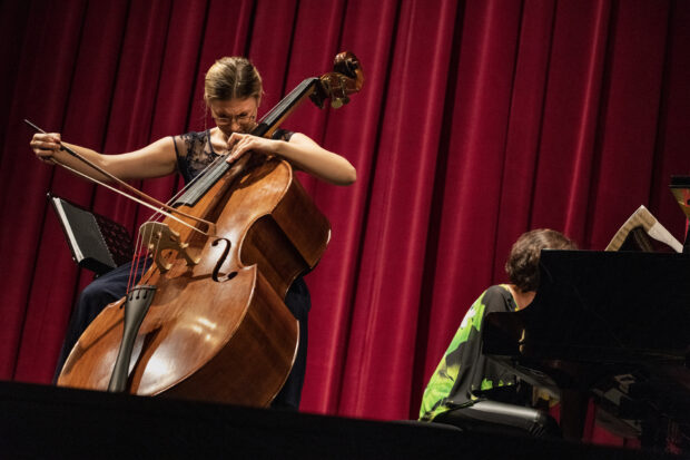 A woman passionately playing the double bass on stage with a pianist in the background, HD Desktop Wallpaper