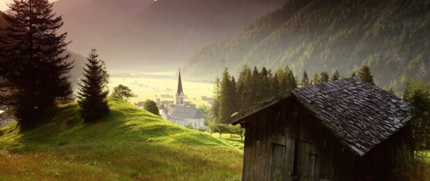 A peaceful alpine village surrounded by green hills and trees in Austria wallpapers, 2K Desktop Wallpaper