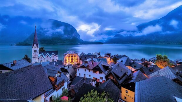 A peaceful alpine village with a church and houses by a lake in Austria, 4K Desktop Wallpaper