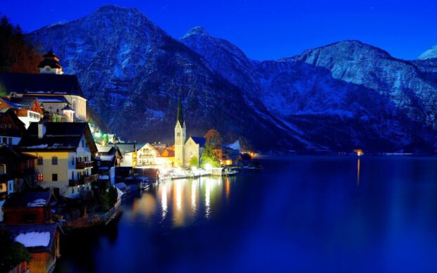 A peaceful night in an Austria village with illuminated houses and mountains reflecting on the lake, HD Desktop Wallpaper