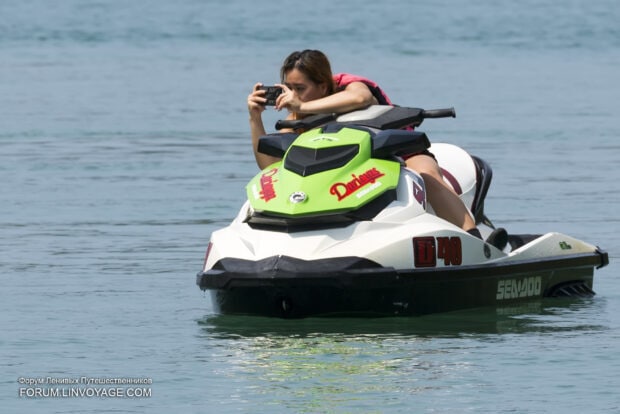 A person is taking a picture while riding a jet ski on calm water, HD Desktop Wallpaper