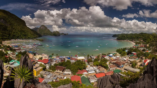 A panoramic view of a coastal town in the Philippines with turquoise waters and lush green mountains